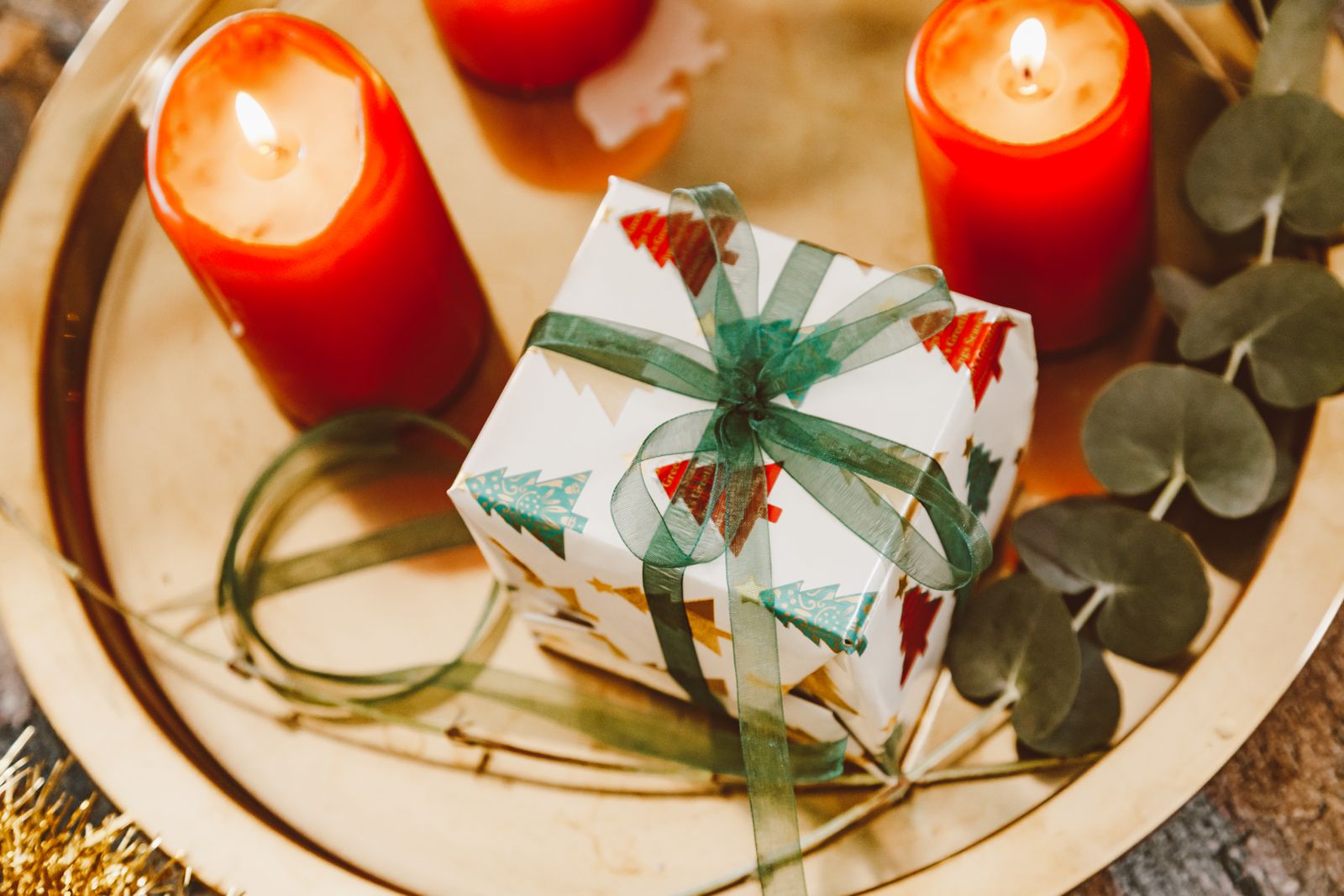 Wrapped gift box beside candles and eucalyptus