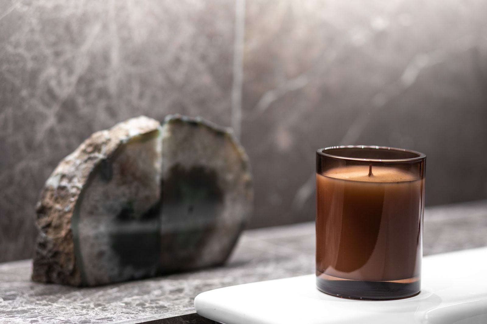 Amber candle beside a slice of agate on a stone counter